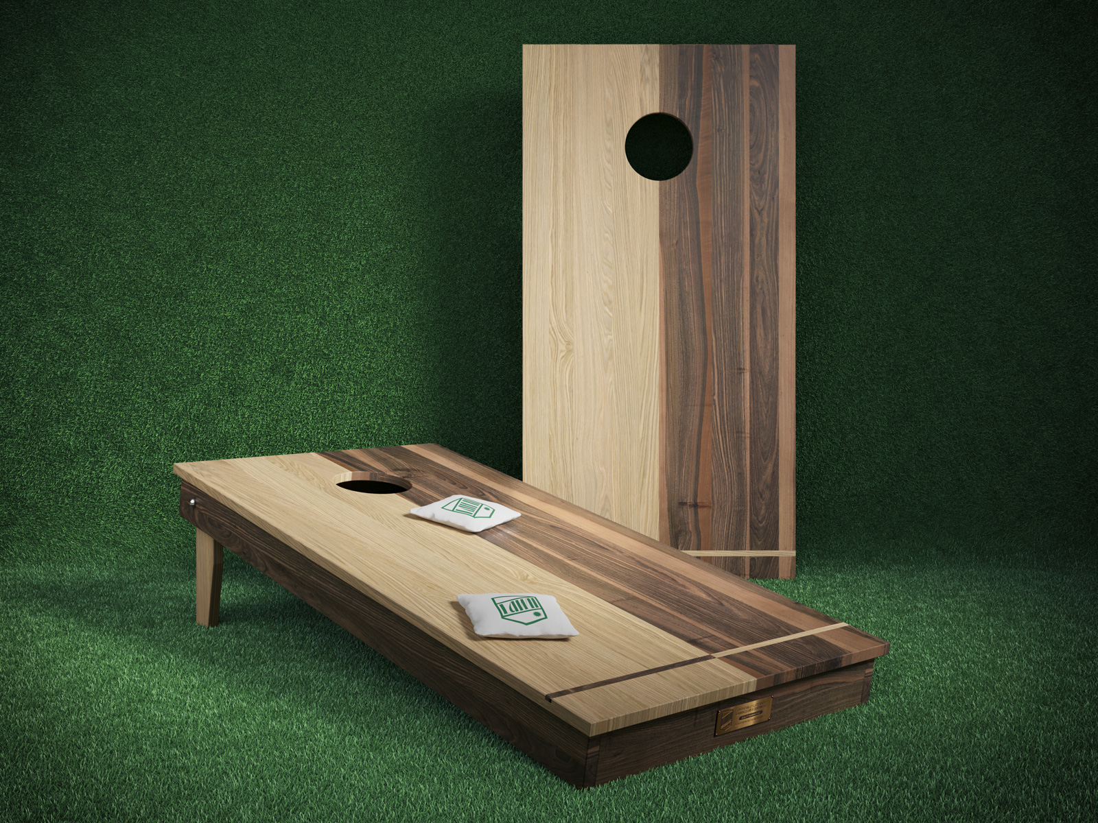 A set of gaming of equipment for the game cornhole, made of rich dark and light wood, set against a green turf background.